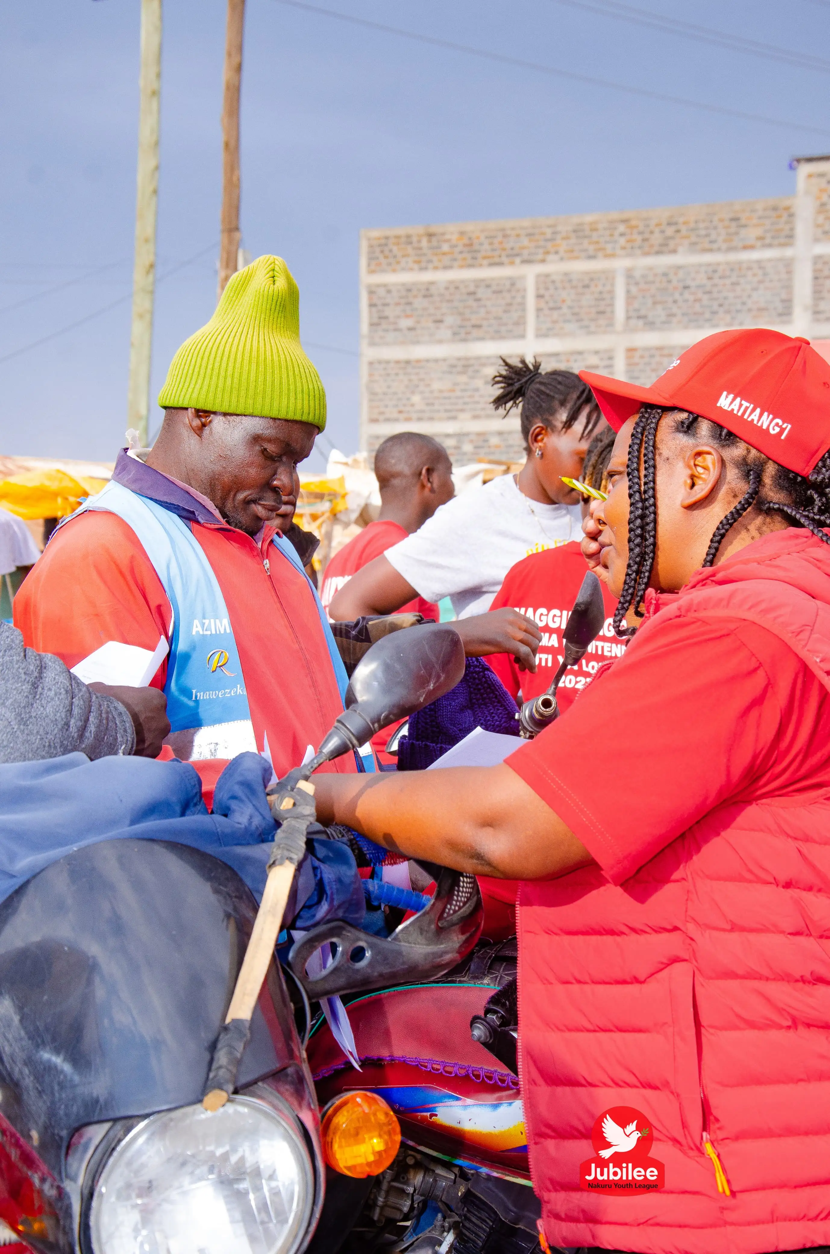 Woman in a red jacket on a motorbike talking to riders