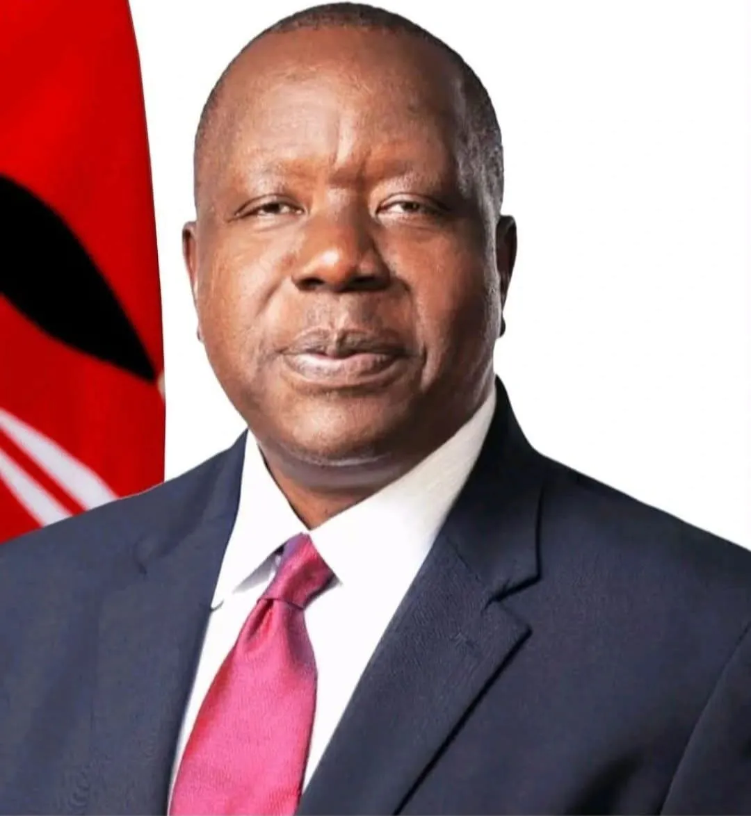 Formal portrait of Dr Fred Matiang'i beside the Kenyan flag