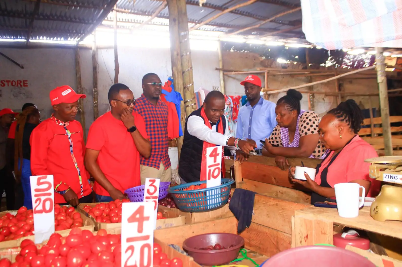 Team in red meeting a vegetable trader behind her tomato stall