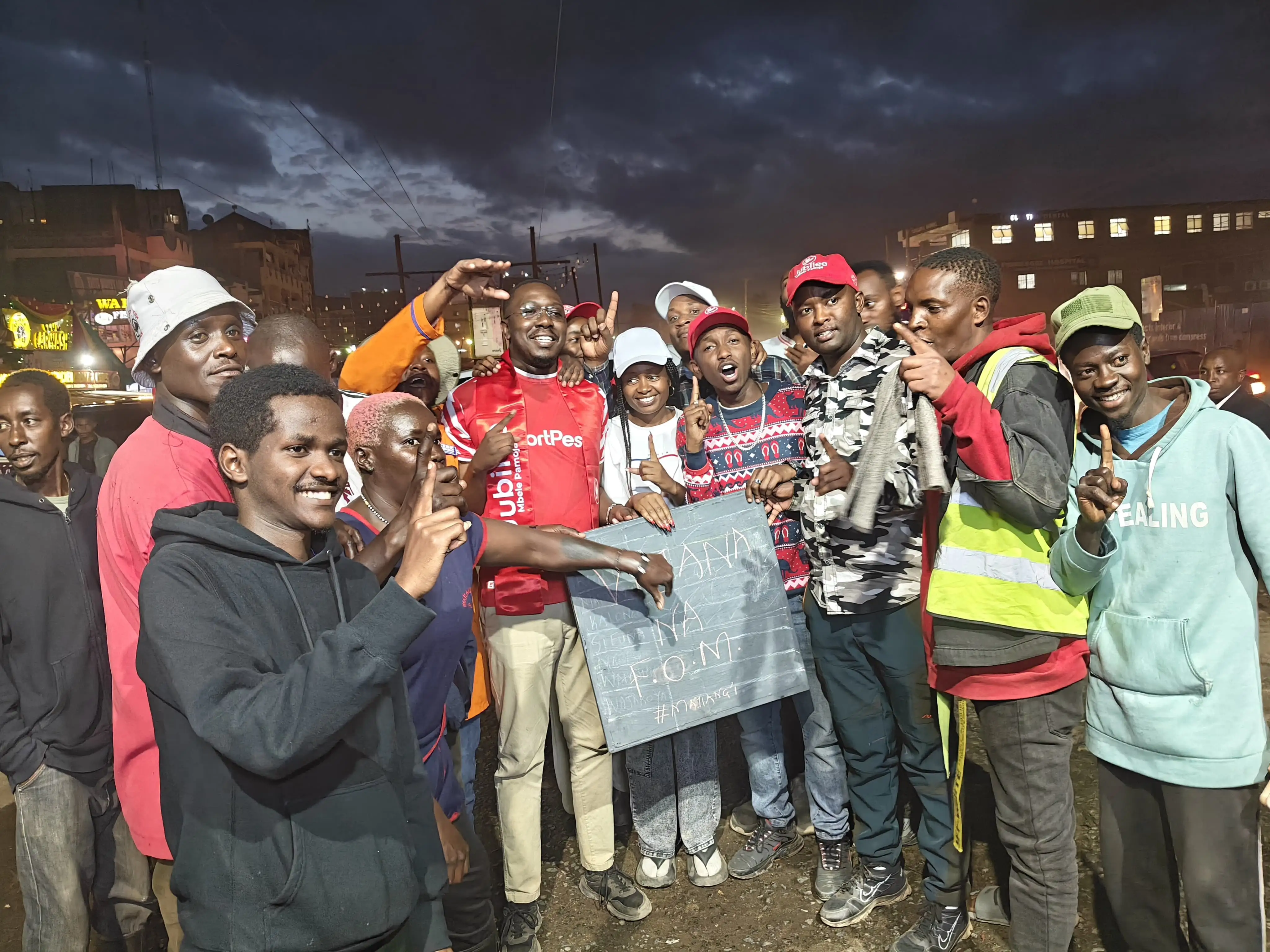 Young people gathered at an evening rally holding a placard