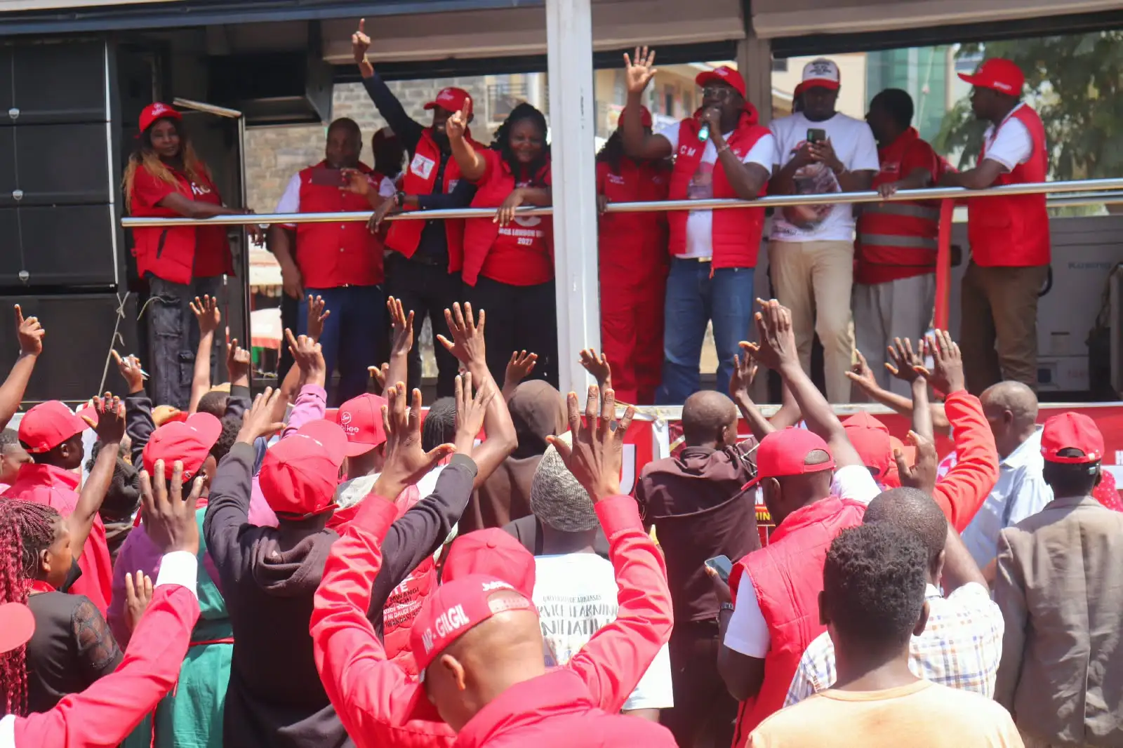 Crowd in red caps with hands raised in front of a stage
